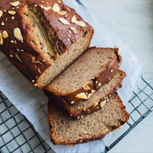 Sliced buckwheat banana bread with ripe bananas and walnuts on a wooden board.