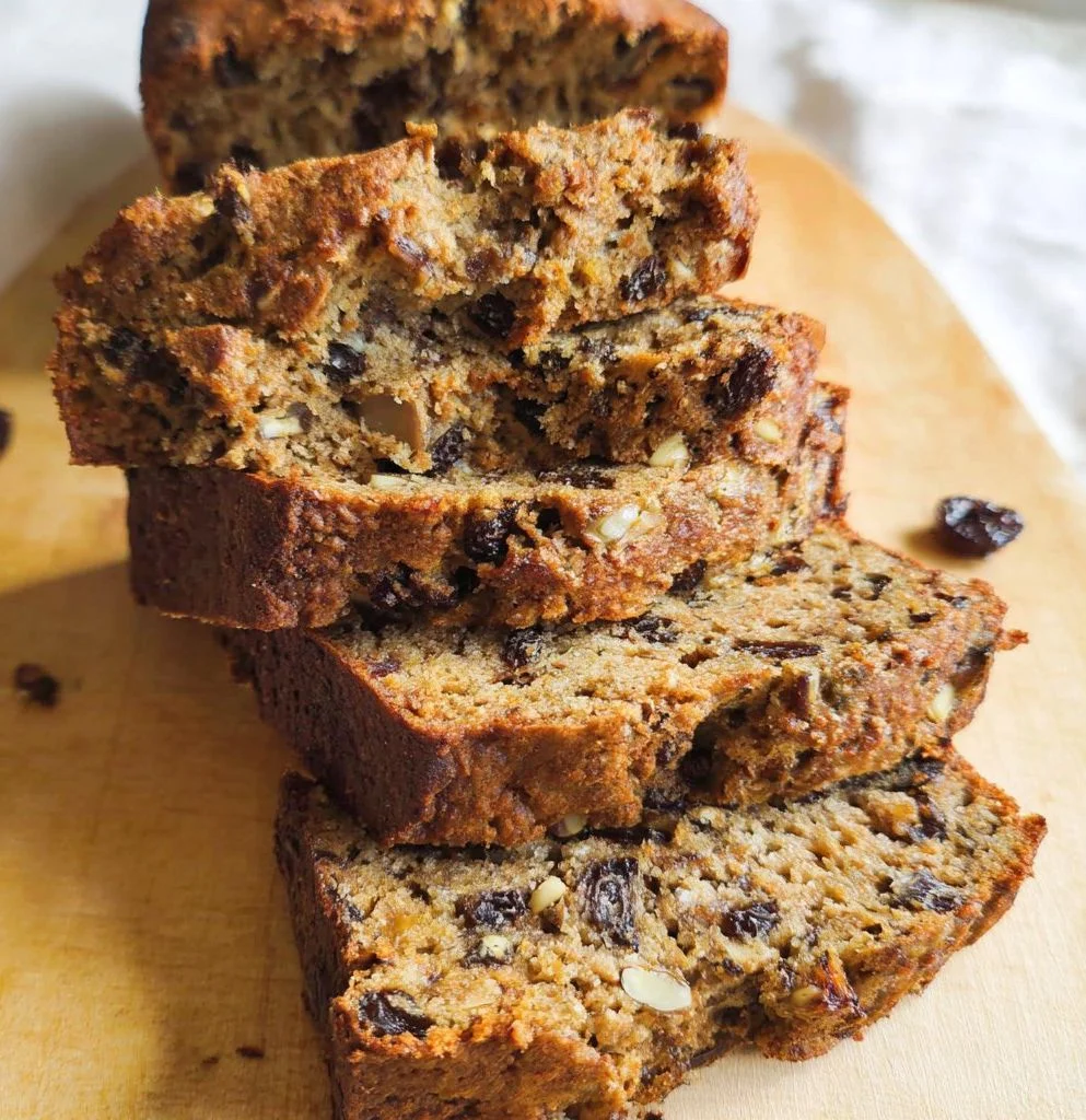 Slice of vegan banana date nut bread on a wooden board
